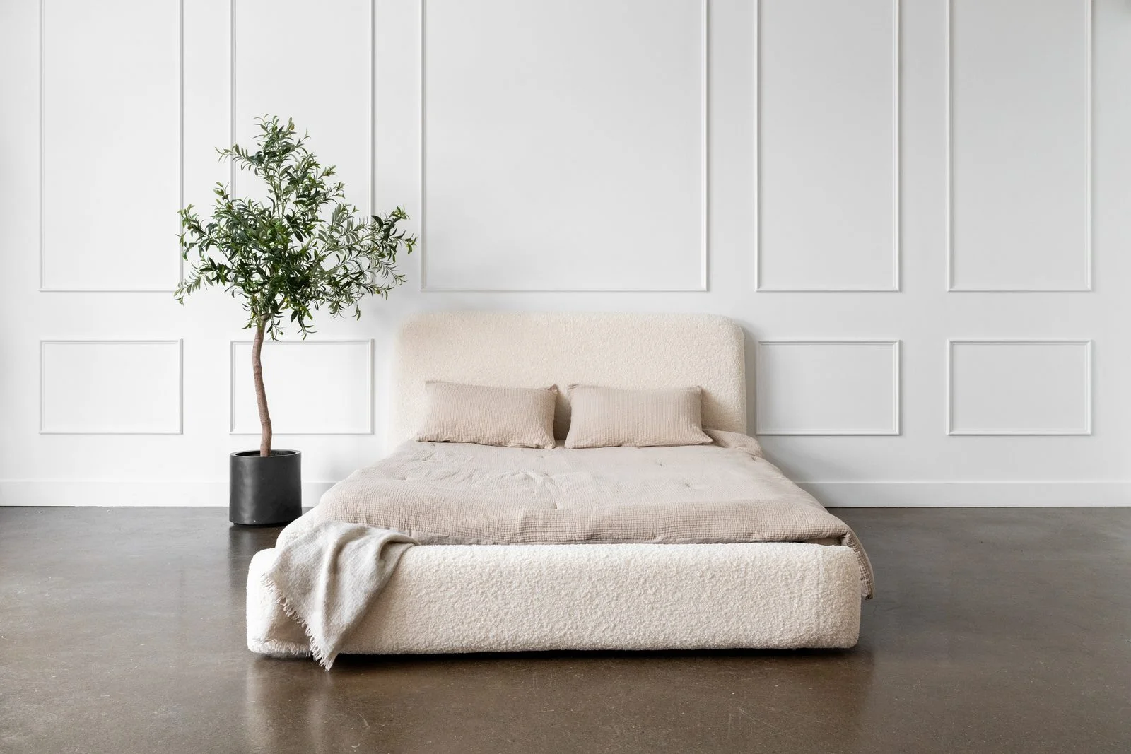 Styled hotel bed with cream bouclé upholstery and neutral linens