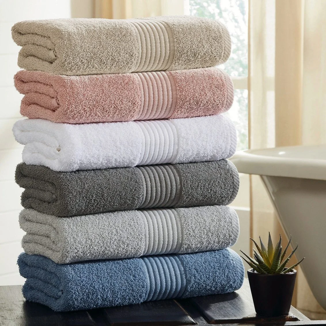 Stack of folded towels in taupe, blush, white, grey and blue