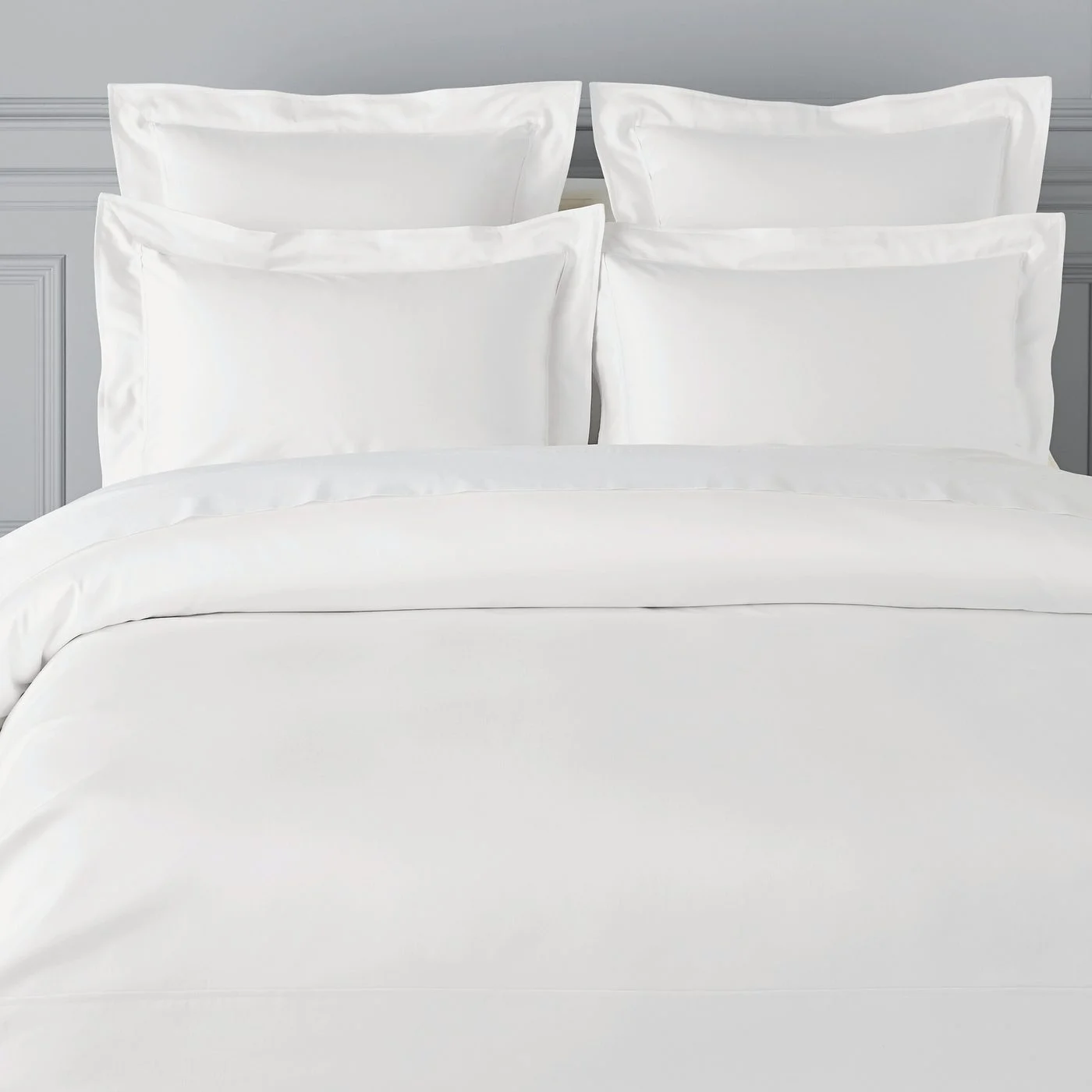 Neatly dressed white duvet cover and pillow shams on a hotel bed