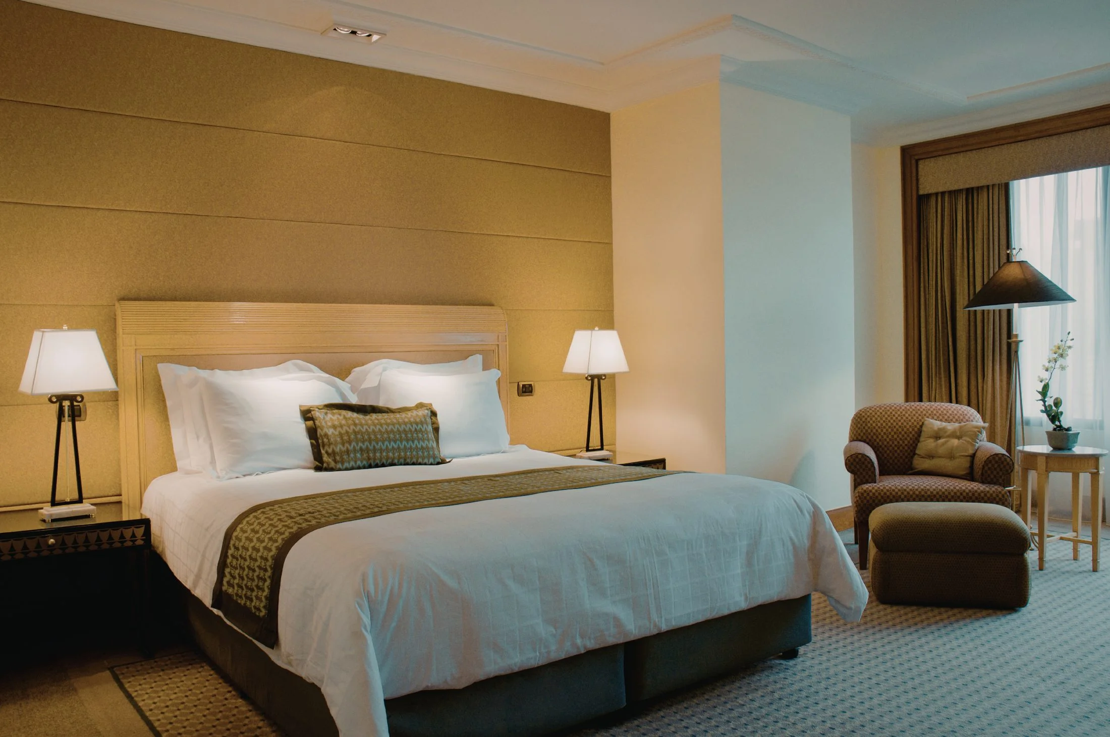Elegantly dressed hotel bed with crisp white linens in a warm-toned guest room